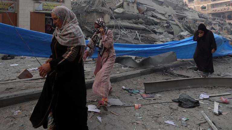 Mujeres palestinas caminando entre los escombros en el barrio de Nasr, en la ciudad de Gaza.
