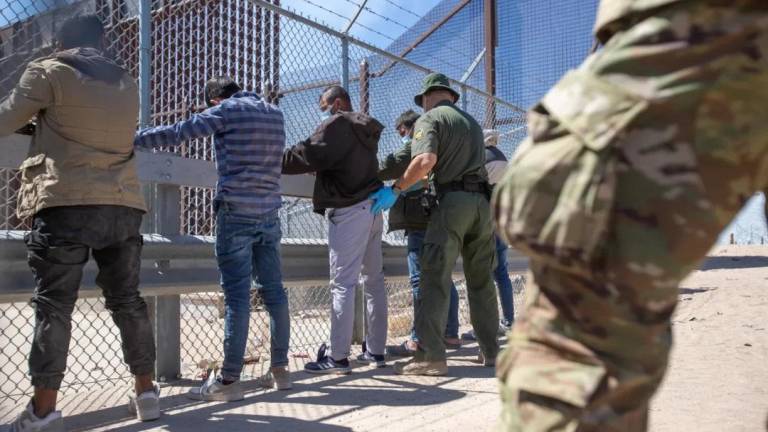 Agentes de la patrulla fronteriza revisan a migrantes que se entregaron cerca de la puerta 42 del muro fronterizo.