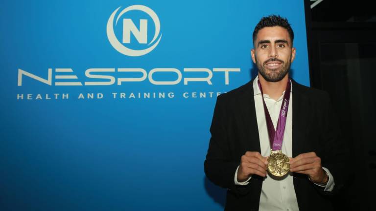 Néstor Vidrio posa con su medalla olímpica al inaugurar su clínica de rehabilitación deportiva.