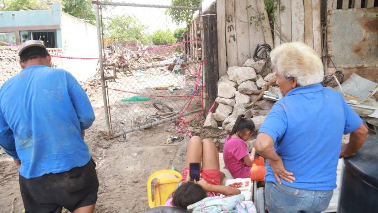 Doña Rosa Isela y su familia esperan afuera de lo que era su vivienda, en la Colonia Villas del Sol.