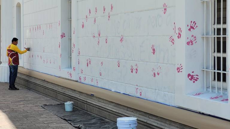 Apenas dos horas después de la intervención del Palacio Municipal por colectivos feministas, personal del Ayuntamiento de Culiacán cubre las pintas con pintura blanca.