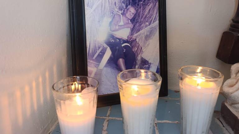 La fotografía de don José Roberto es iluminada por velas. La fotografía de don José Roberto es iluminada por velas.