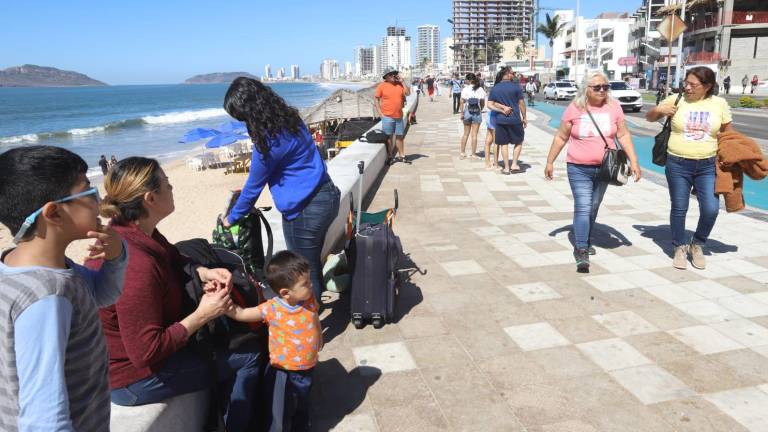 Turistas recorren el malecón de Mazatlán con maleta en mano