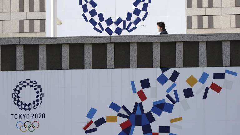 Un hombre con mascarilla camina frente al logotipo de los Juegos Olímpicos de Tokio, el miércoles 17 de febrero de 2021.