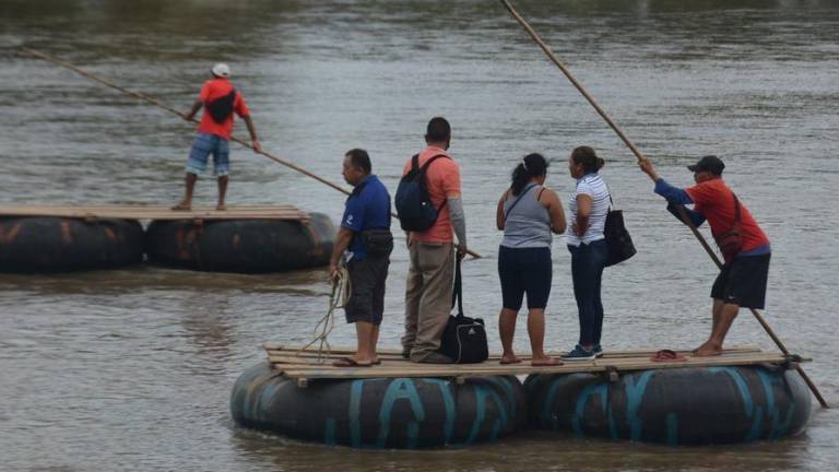 Un grupo de personas atraviesa en balsa el río Suchiate, cruzando la frontera entre Guatemala y México.