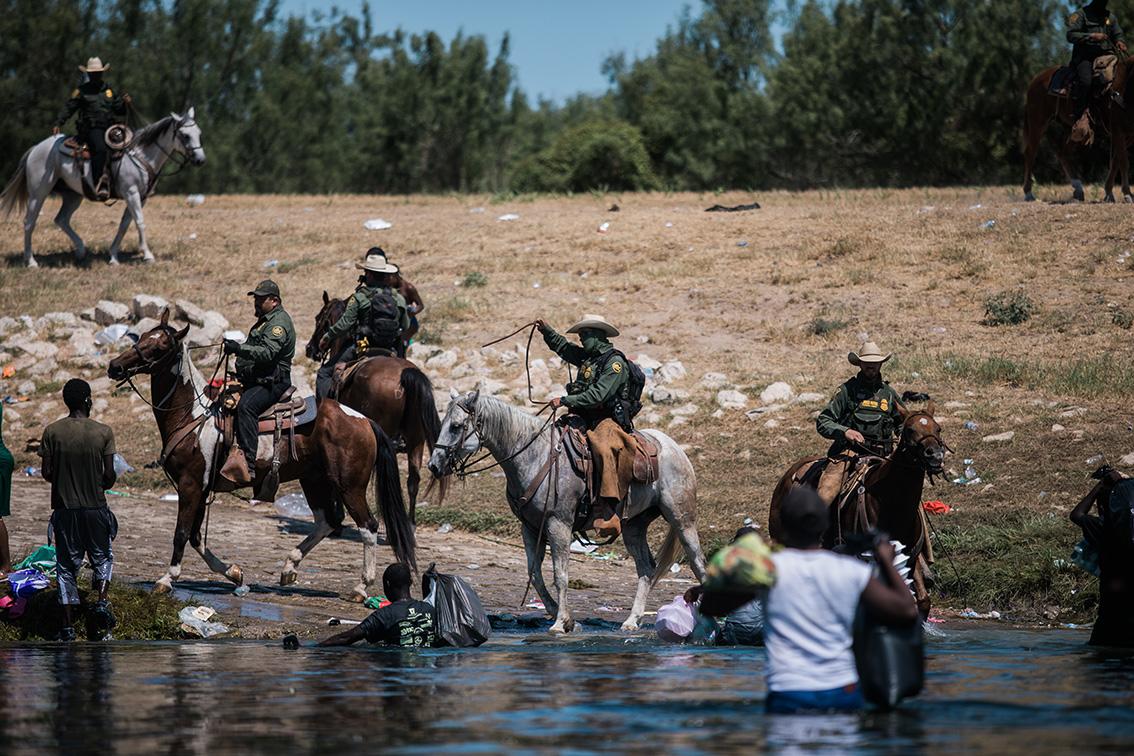 $!Oficiales de Aduanas y Protección Fronteriza de Estados Unidos intentan contener con caballos a los migrantes haitianos que cruzan el Río Bravo desde Ciudad Acuña, México, hacia Del Río, Texas.