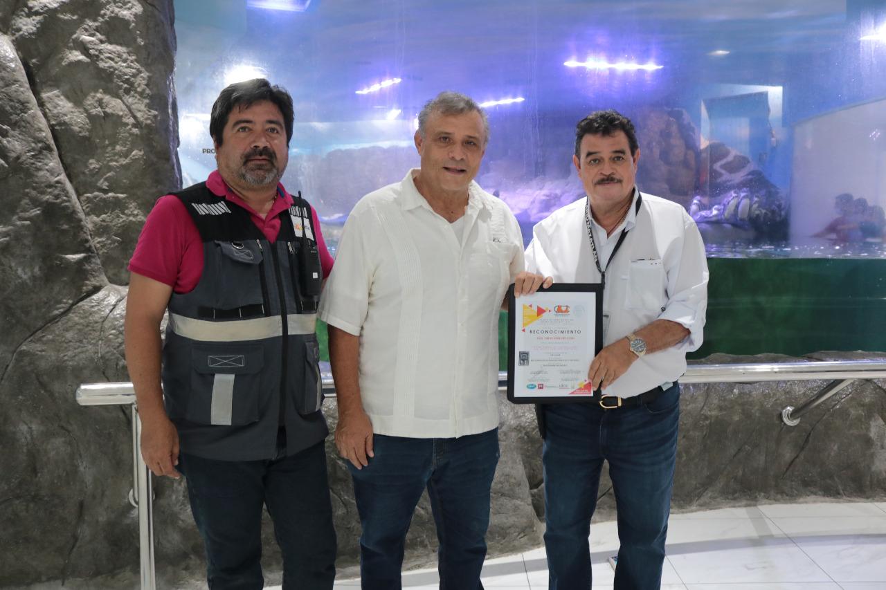 $!El galardonado (al medio) muestra el reconocimiento, teniendo como fondo el Pingüinario de Mazatlán.