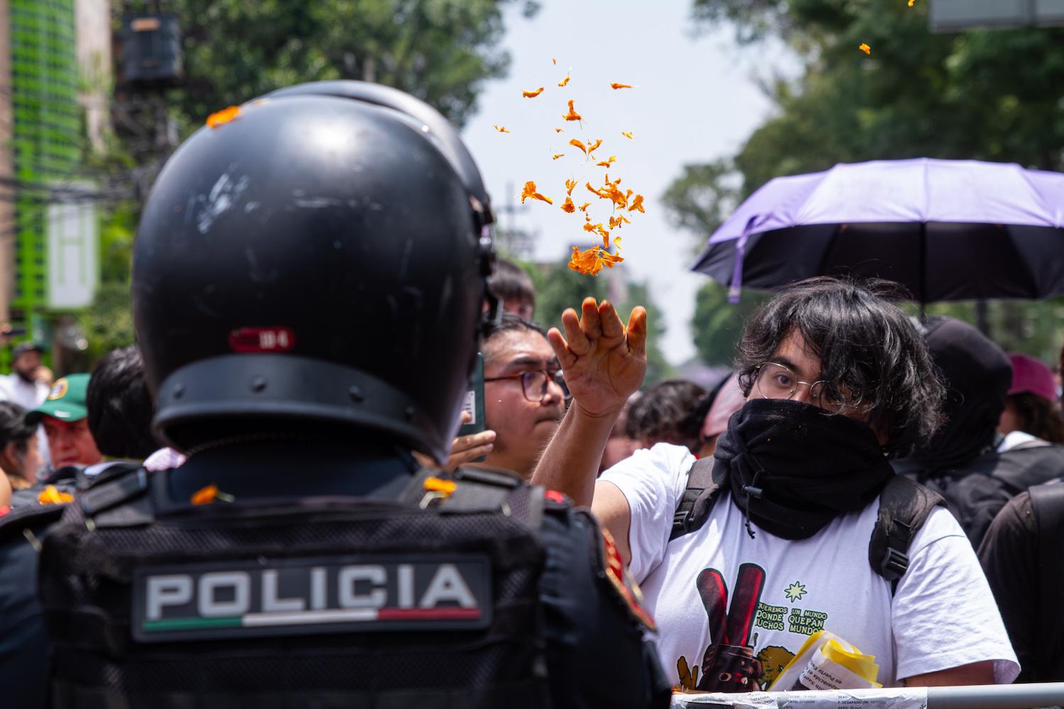 $!Una manifestante arroja pétalos al policía que le impide el paso durante la movilización realizada el día de la inauguración del Mundial.