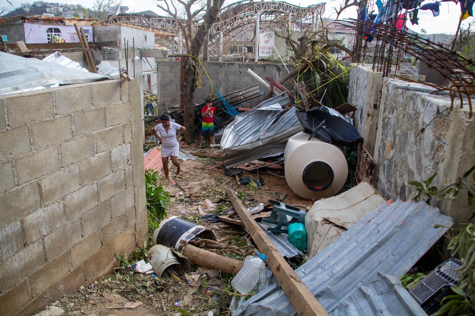 $!Pobladores caminan a través de escombros para llegar a sus casas.