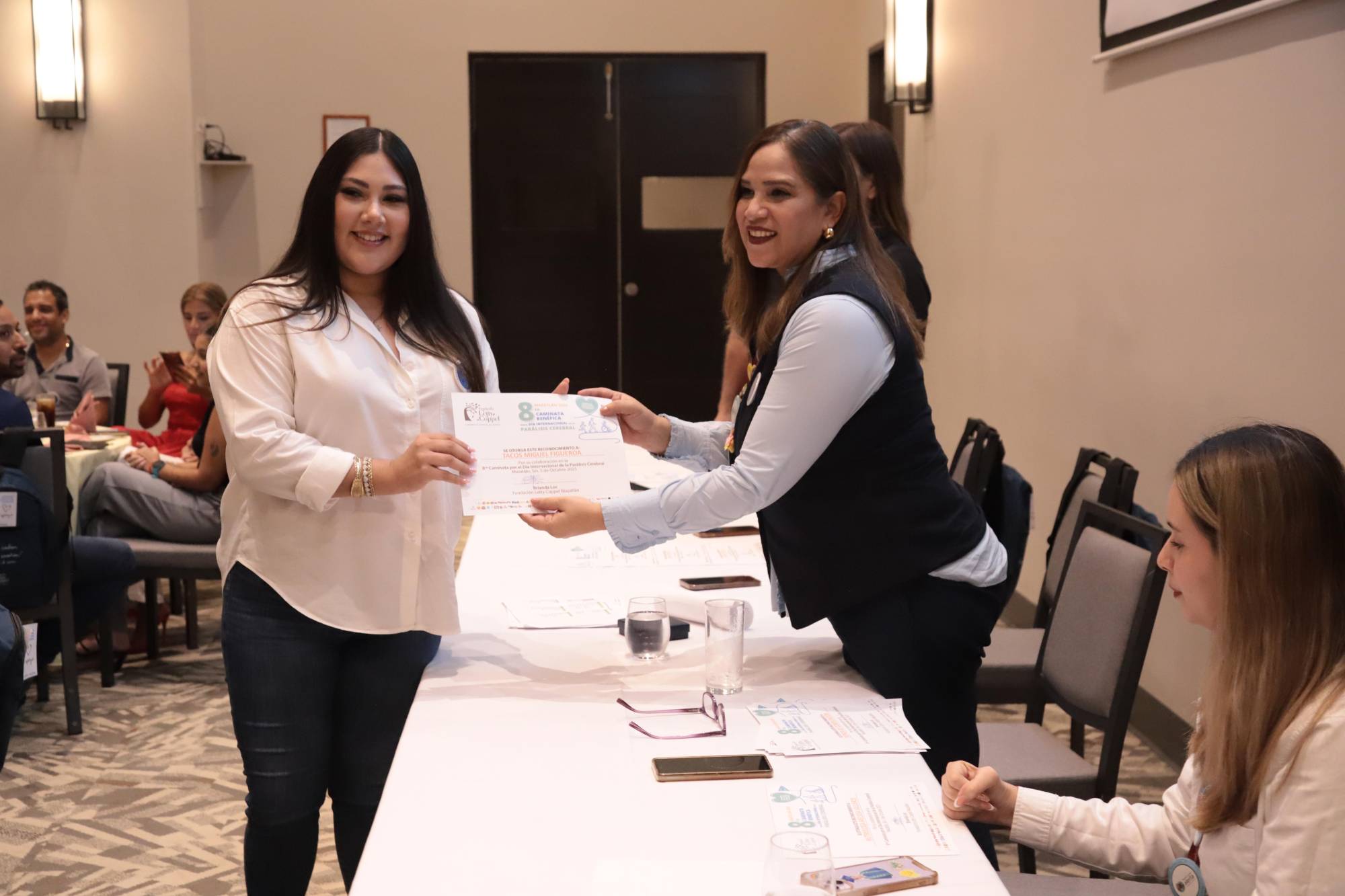 $!Brissia Figueroa, de Tacos Figueroa, recibe el reconocimiento de manos de Daniela Novelo, de la Fundación Grupo Alerta.