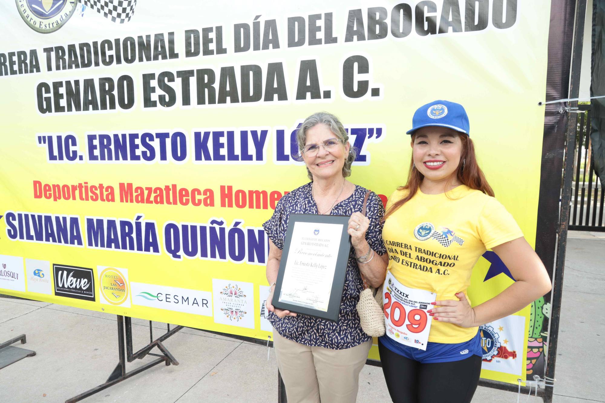 $!Adriana Morales, presidenta del colegio, hace entrega del reconocimiento de Ernesto Kelly a su hermana Blanca Kelly, ya que el homenajeado se encontraba fuera de la ciudad.