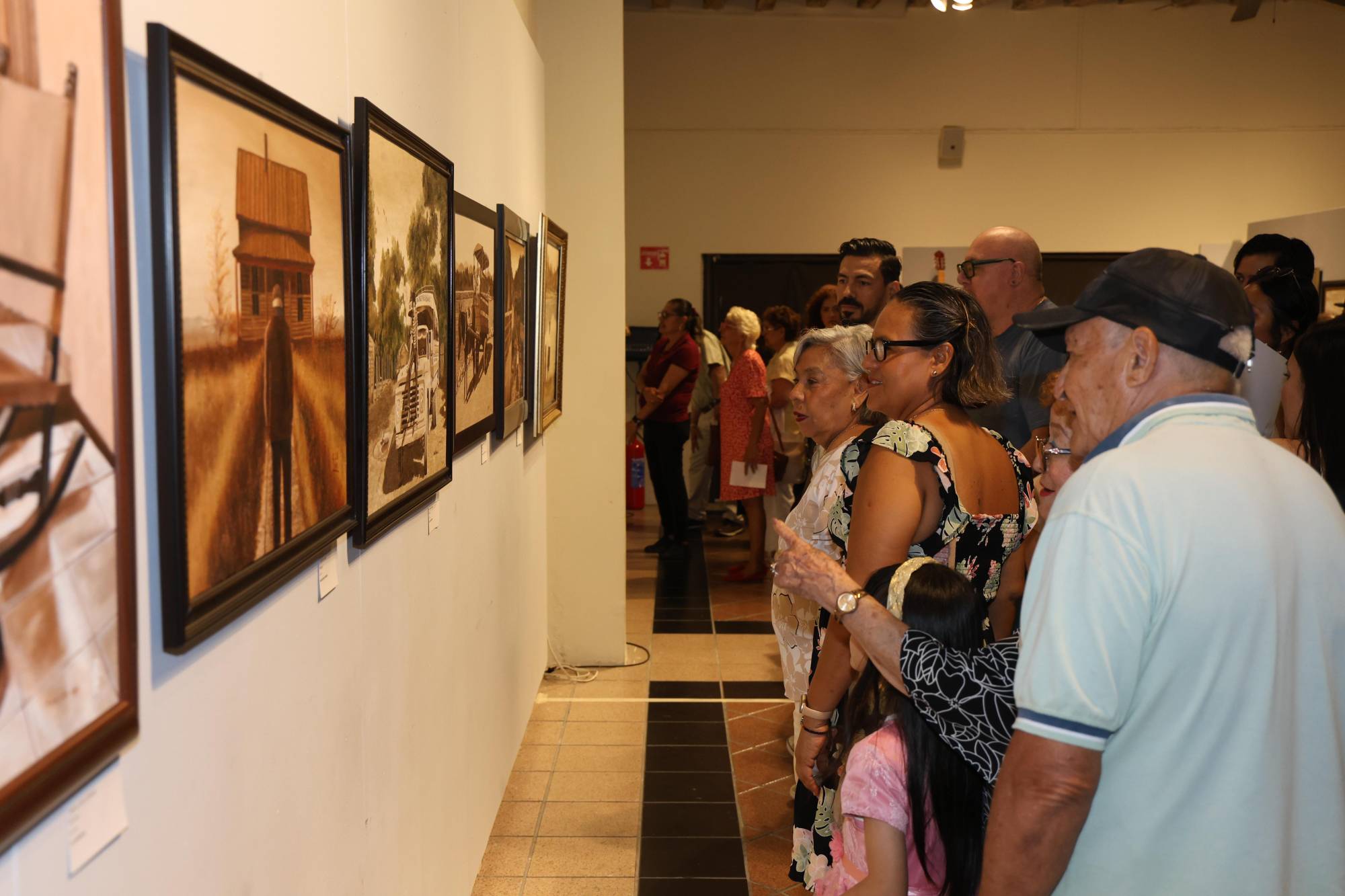 $!Asistentes recorren la galería y aprecian las obras que integran la exposición durante la velada cultural.