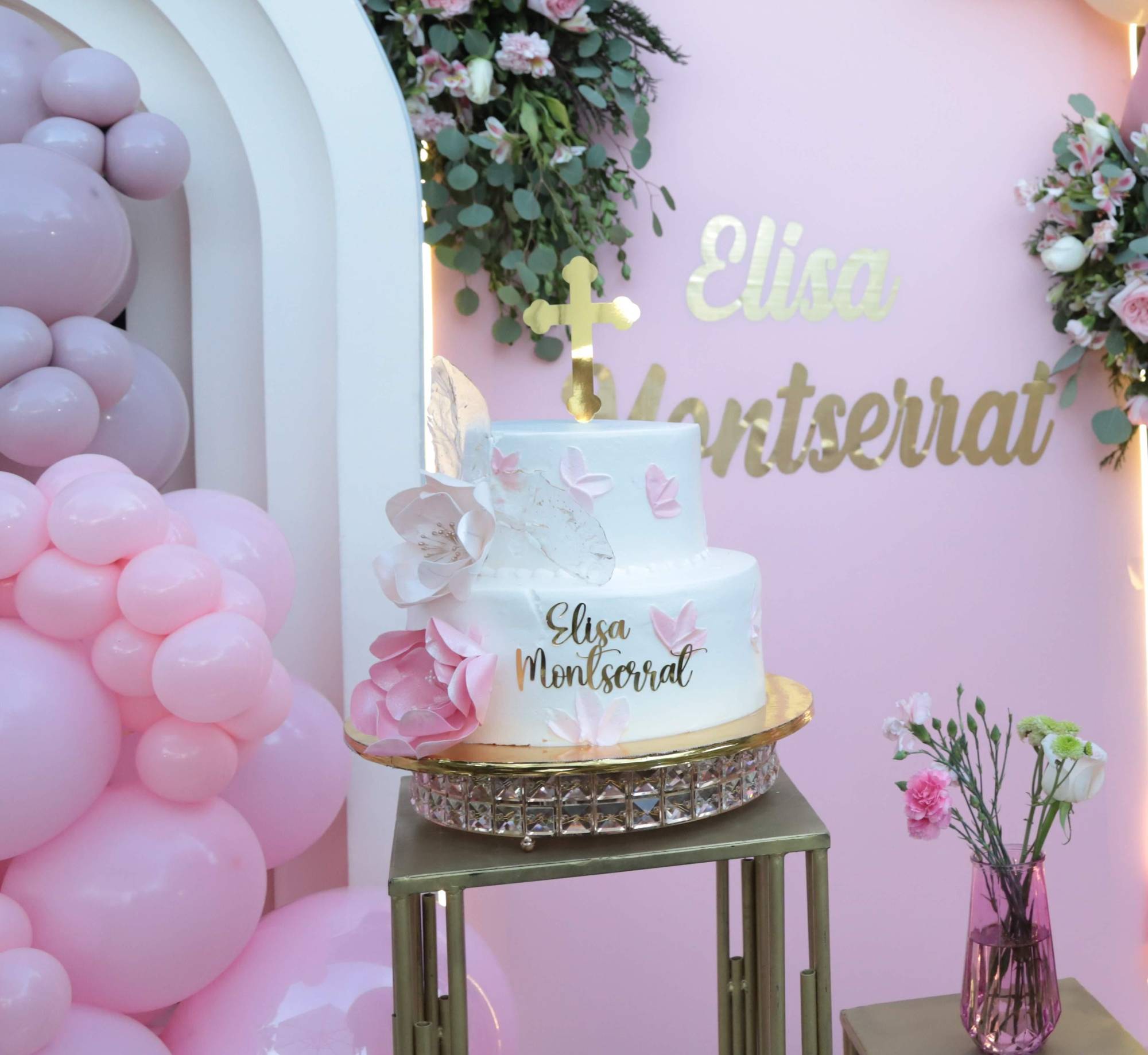 $!Un pastel de dos pisos en color blanco, con decorados con una curz, flores y mariposas, y el nombre de Elisa Montserrat, lució en la mesa principal.