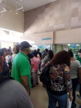 Decenas de derechohabientes del IMSS hacen fila para surtir las recetas médicas en la farmacia.