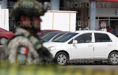 Autoridades resguardan el área del estacionamiento donde fue asesinado un hombre al interior de su vehículo.
