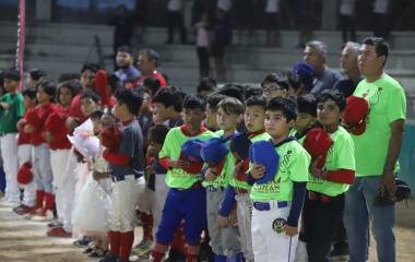 Los pequeños peloteros rinden honores a la bandera durante la ceremonia inaugural.