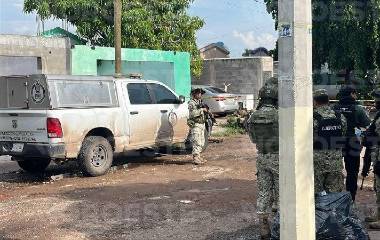 Agentes de investigación resguardan la vivienda donde tres personas fueron asesinadas a balazos.