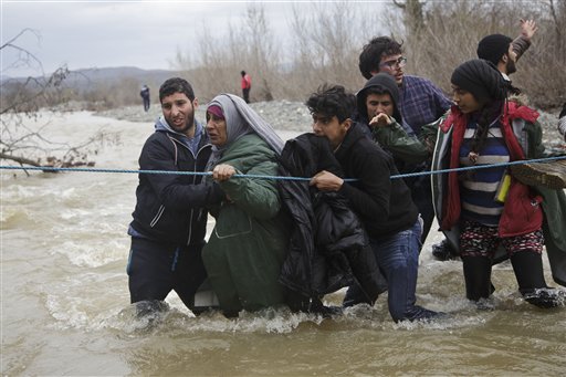 Cientos de migrantes cruzan un río que separa a Grecia y a Macedonia.