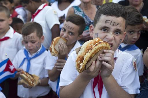 Niños reciben un pedazo de pizza mientras esperan el paso de las cenizas de Fidel Castro.