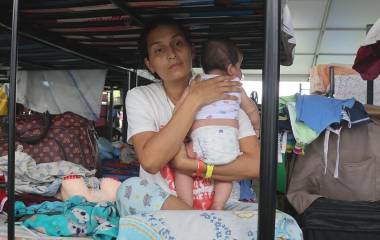 Una mujer desplazada cuida a su hijo de dos meses en un campamento provisional en La Guaira, Venezuela.