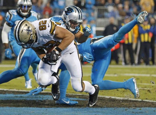 Coby Fleener (82) anota, mientras David Mayo (55) defiende.