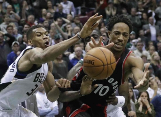 Giannis Antetokounmpo y DeMar DeRozan intentan recuperar un balón perdido.