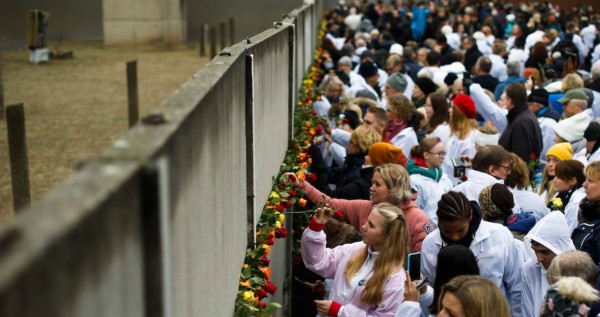 Cientos de personas colocan rosas en lo que queda en pie del Muro de Berlín.