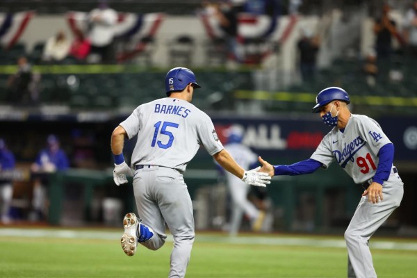 Austin Barnes es felicitado por el coach de la tercera base tras dar su jonrón.