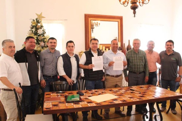 Los funcionarios muestran el convenio firmado.