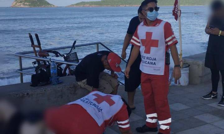 Paramédicos de Cruz Roja atienden al bañista que resultó lesionado en la cabeza al ser arrojado por una ola a una zona rocosa.