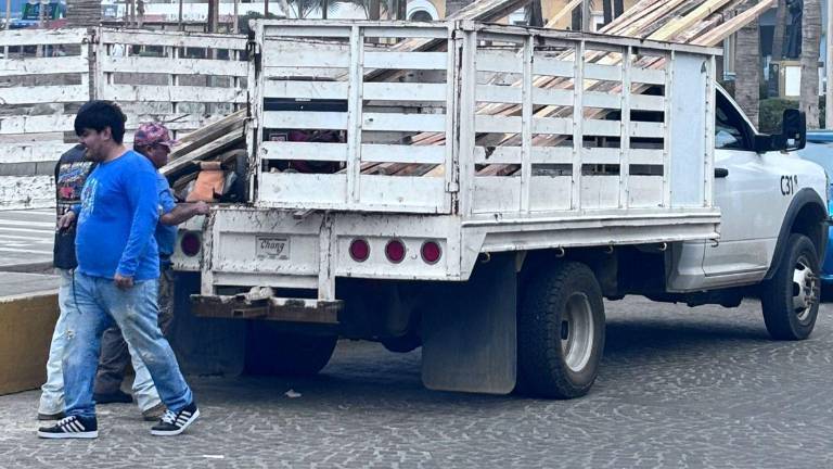 Los trabajadores colocan maderas en las banquetas de Olas Altas.