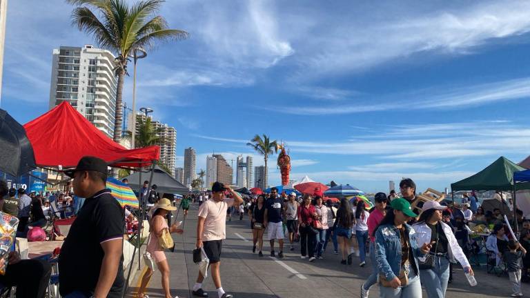 Familias y grupos de amigos esperan el paso del desfile sobre el malecón de Mazatlán.