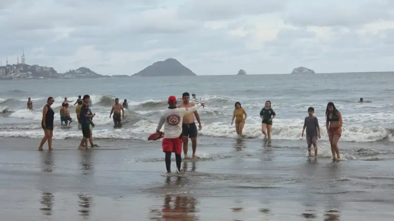 Personal de Salvamento da instrucciones a los bañistas por el mar de fondo.