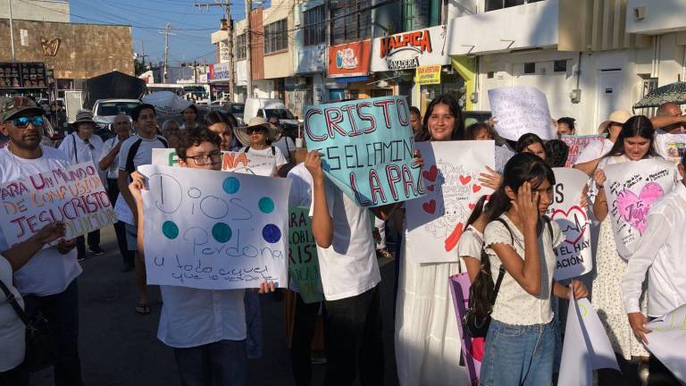 Participantes de la “Marcha por Jesús y por la Paz” avanzan por las calles del Centro de Mazatlán, portando banderas y pancartas con mensajes de unidad y espiritualidad.