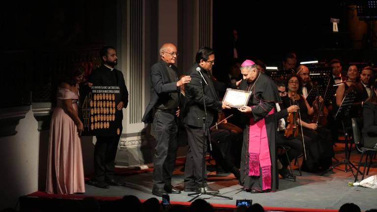 El Obispo Mario Espinosa Contreras recibe un reconocimiento de manos del Padre Daniel Arellano Macías.