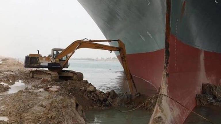 Una retroexcavadora realiza maniobras de dragado para poder liberar al buque carguero.