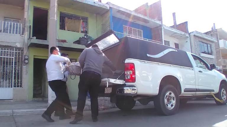 Personal de la funeraria recoge el cuerpo.