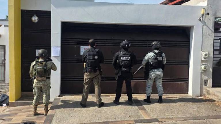 Personal militar, policial y de la FGR resguardan el armamento y explosivos asegurados en un domicilio local.