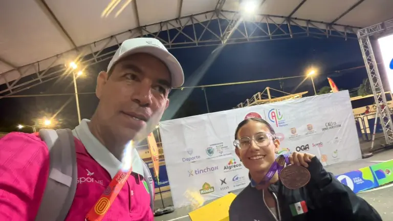 Silvana Quiñones muestra su medalla ganada, al lado de su entrenador Juan Antonio Castellanos Velarde.