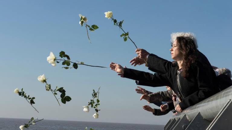 Visitantes lanzan flores blancas al Río de la Plata como símbolo de respeto en el Parque de la Memoria, Buenos Aires, Argentina.