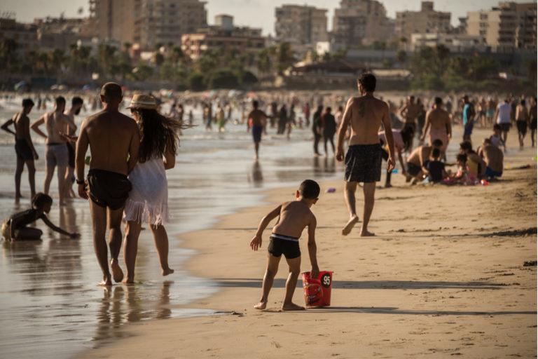 $!Los veraneantes atestan las amplias extensiones de arena de la playa pública de Tiro, en Líbano, y disfrutan de las aguas refrescantes bajo el implacable sol de julio.