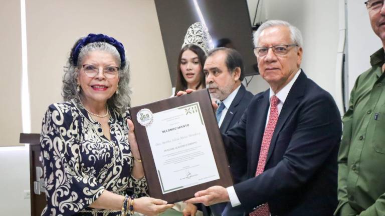 Bertha Alicia Mena Mendoza recibe su reconocimiento de manos de Jesús Aarón Quintero Pérez.