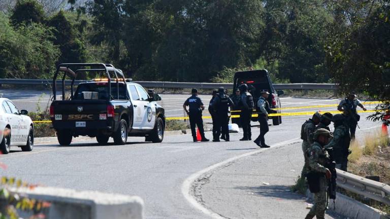 Policías y peritos de la Fiscalía resguardan la autopista Mazatlán-Culiacán tras el ataque a un joven que perdió la vida.