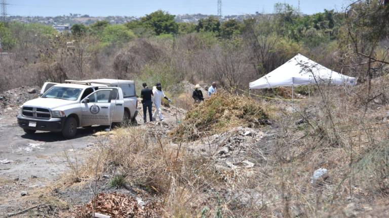 Personal de la Fiscalía de Sinaloa revisa la zona donde fueron localizados los cuerpos semienterradas de tres personas.