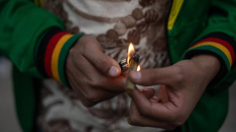 Un joven enciende un cigarrillo de mariguana para autoconsumo.