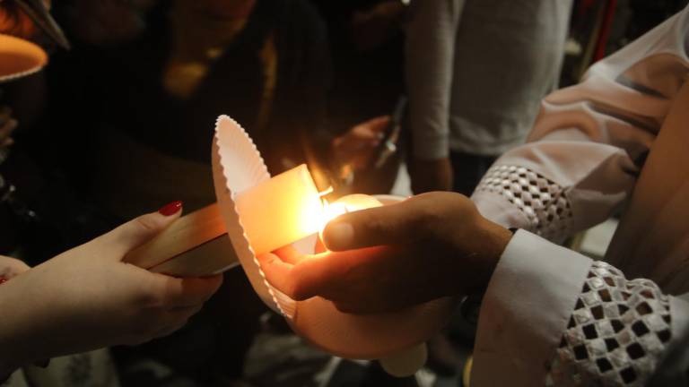 Fieles encendieron sus velas durante la bendición del fuego en la Catedral de Mazatlán, en un rito que simboliza la luz de Cristo resucitado.