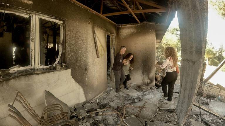 Hadas Kalderon saliendo de la casa quemada de su madre, con ayuda de familiares.