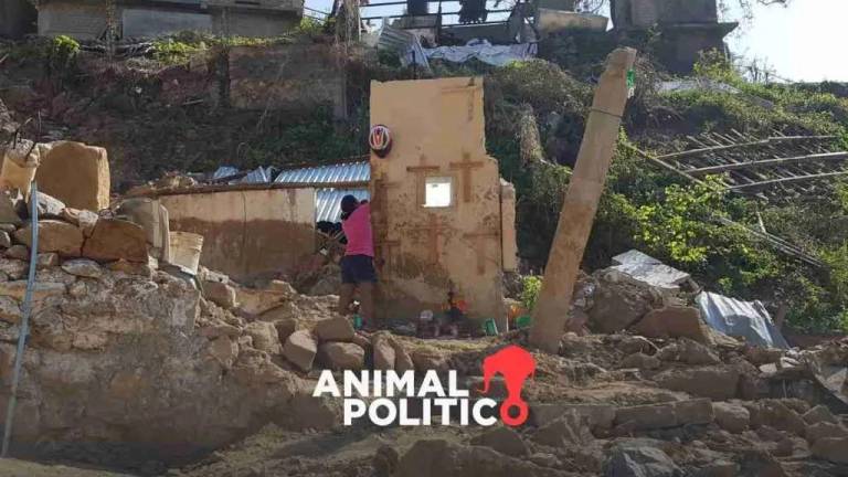 En la imágen, una mujer coloca cruces en la única pared que quedó en pie de la casa de sus vecinos, quienes murieron por un deslave causado por el huracán Otis, en la parte alta de Acapulco.