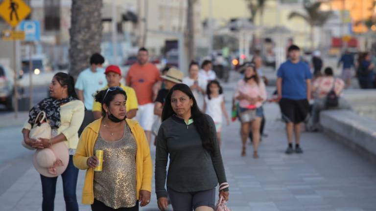 Gente con y sin cubrebocas paseando en el malecón de Mazatlán.