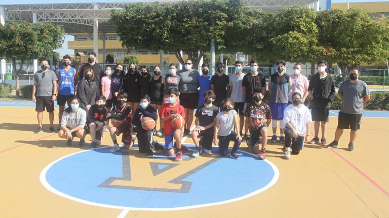 Papás, entrenadores y jugadores de baloncesto se toman la fotografía del recuerdo.